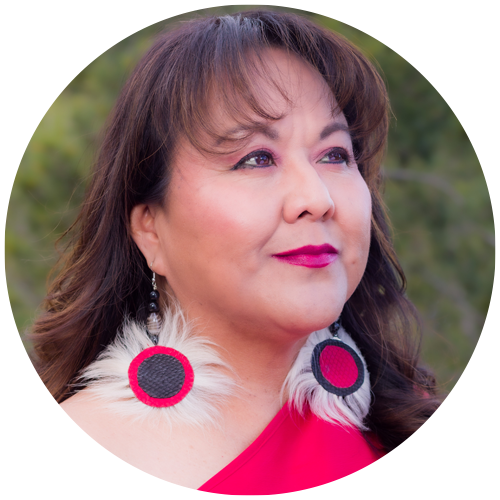 Headshot of Vickie Oldman with earrings in front of foliage